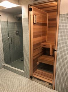 a sauna in the corner of a bathroom with tiled walls and flooring,