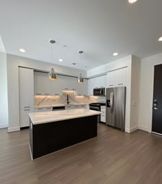 an empty kitchen with stainless steel appliances and white cabinets