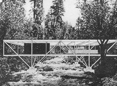 an old photo of a bridge over a stream in the woods with trees around it