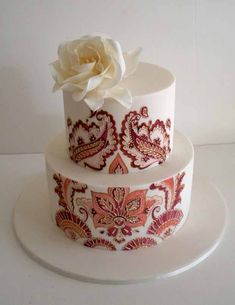 a three tiered cake decorated with red and white paisley designs on a platter