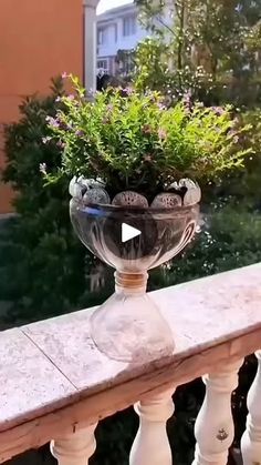 a glass vase filled with flowers sitting on top of a wooden rail next to a building