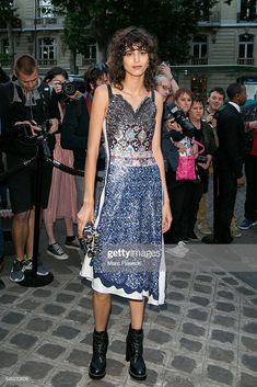 a woman in a blue and white dress standing on the street