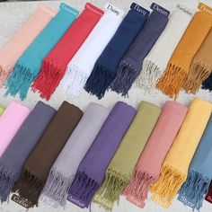 many different colors of scarves laid out on a table with the names of each scarf