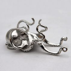 an octopus brooch is shown on a white surface with silver colored metal accents and intricate details