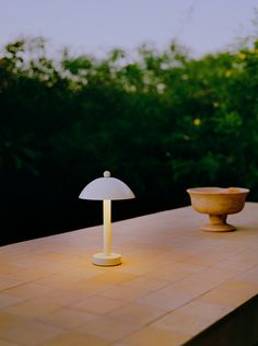 a lamp sitting on top of a table next to a bowl