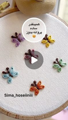 there are many small butterflies on the embroidery board, which is decorated with words and pictures