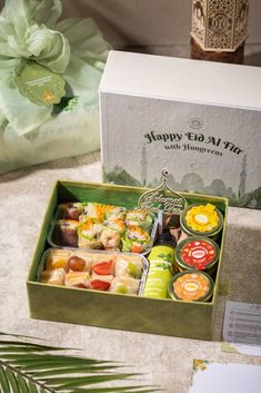 an assortment of sushi in a green box on a table next to other items