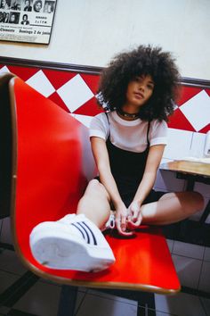 a young woman sitting on top of a red bench in a restaurant next to a laptop computer