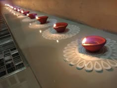 there are many bowls on the table with candles in them and one is lit up