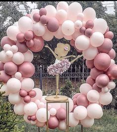 a pink and white balloon arch in the shape of a ballerina on a stand