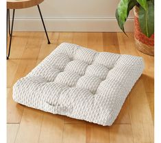 a white mattress sitting on top of a wooden floor next to a potted plant