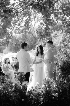 a bride and groom standing under a tree during their wedding ceremony