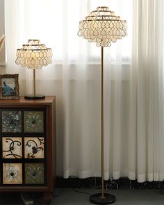 two floor lamps sitting on top of a table next to a window