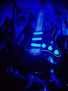 an electric guitar lit up in the dark with blue light from its neck and bridge