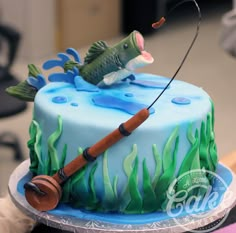 there is a cake with a fishing theme on it and a fish hooked up to the pole