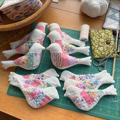 several pieces of fabric laid out on a cutting board with scissors and sewing supplies in the background