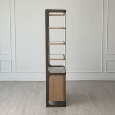 a tall wooden shelf sitting on top of a hard wood floor next to a white wall