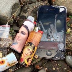 an image of a cell phone and other items laying on the ground next to rocks