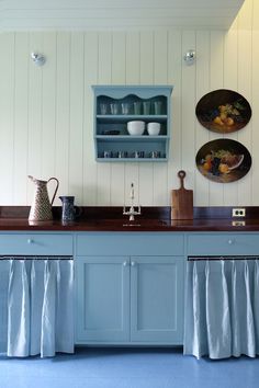 a kitchen with blue cabinets and counter tops in front of two plates hanging on the wall