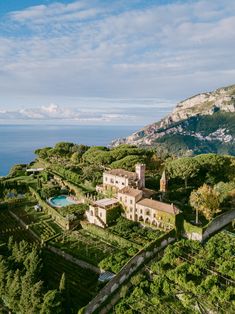 an aerial view of a house surrounded by trees and greenery in front of the ocean