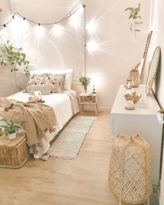 a bedroom with white walls and wooden flooring is decorated in neutral tones, including greenery