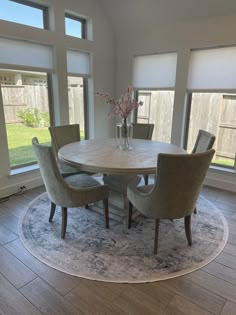 a dining room table with four chairs and a vase filled with flowers on top of it