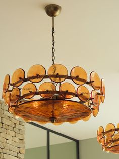 a chandelier hanging from the ceiling in a room with brick wall and windows