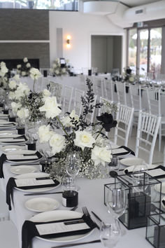 the tables are set with white flowers and black napkins for an elegant wedding reception