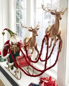 two reindeer sleighs with santa claus and other decorations on the window sill