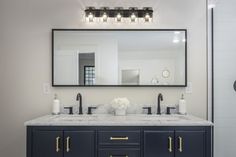 a bathroom vanity with two sinks and a large mirror above it, in front of a walk - in shower