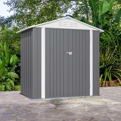 a gray and white shed sitting on top of a stone patio