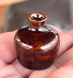 a small brown vase sitting on top of someone's hand