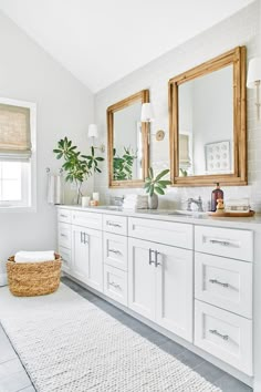 a white bathroom with two mirrors above the sinks and a rug on the floor in front of it