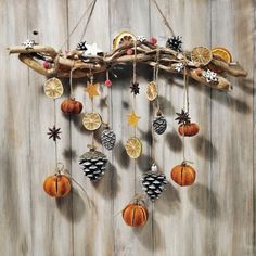 a wooden wall with ornaments hanging from it's sides and pine cones on the branches