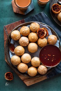 some food is sitting on a plate next to cups and sauces