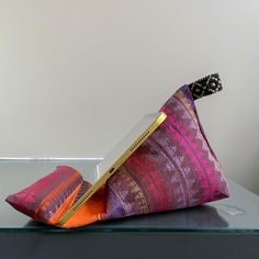 a pair of colorful pillows sitting on top of a glass table next to a white wall