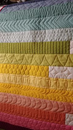 a close up of a colorful quilt on a bed