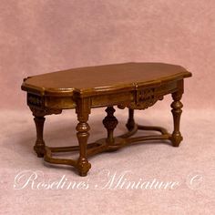 a miniature wooden table sitting on top of a white floor next to a pink wall