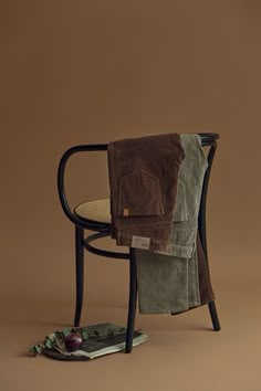 a chair with a blanket on it and an apple sitting next to it in front of a brown background