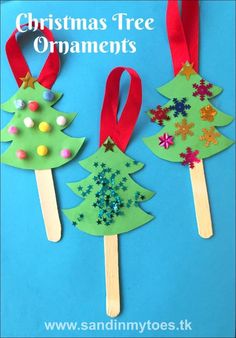 christmas tree ornaments made out of popsicle sticks on a blue background with red ribbon