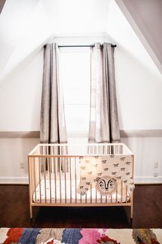 a baby crib in the corner of a room with curtains on the windowsill