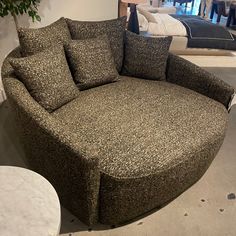 a round couch with pillows on it in a store