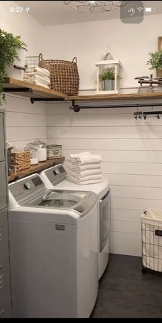 a washer and dryer sitting in a room next to some shelves with plants