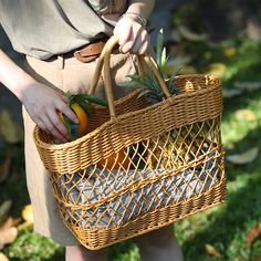 a woman holding a wicker basket with an orange and pineapple in it on the grass