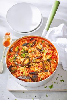 a bowl filled with rice and mussels on top of a table