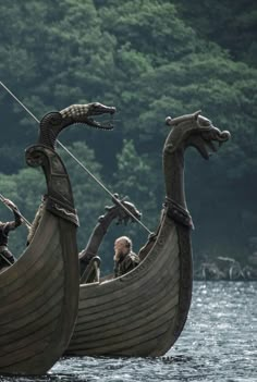 some people are in a boat with two large dragon heads on it's side