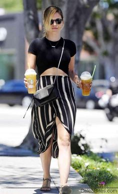 a woman is walking down the street with two drinks in her hand and holding a drink