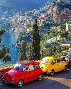 three colorful cars parked on the side of a road next to a body of water