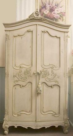 an old white armoire sitting next to a window