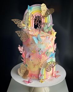 there is a multi layer cake decorated with butterflies and rainbows on the top tier